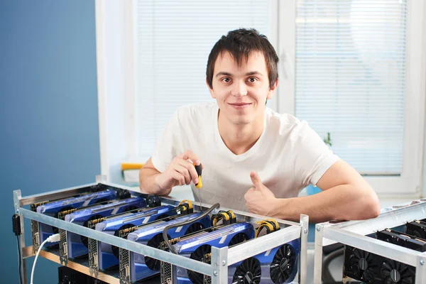 kameraya bakarak ve başparmak cryptocurrency ofiste çıkarım için farm yakınındaki dururken gösterilen genç adam 