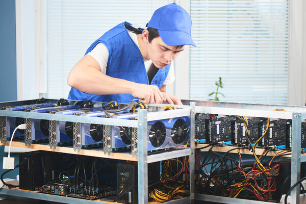  man in uniform setting up farm for extraction of cryptocurrency in laboratory 