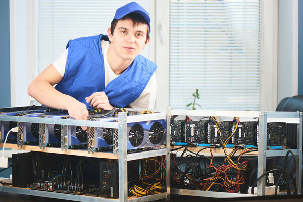 young man in uniform leaning on farm for extraction of cryptocurrency in office 