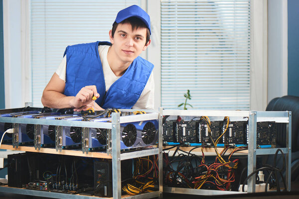 young man in uniform leaning on farm for extraction of cryptocurrency in office 