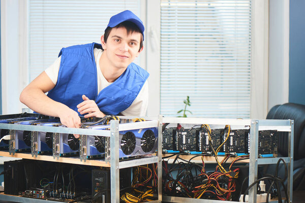 young man in uniform leaning on farm for extraction of cryptocurrency in office 