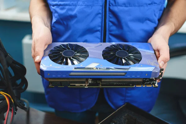 male hands holding video card for setting up farm of bitcoin mining