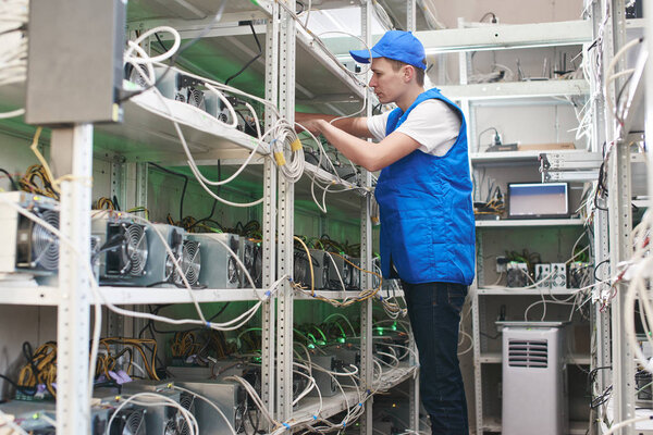 worker checking bitcoin mining farm in laboratory