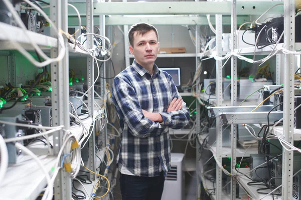 young man with crossed arms standing at cryptocurrency mining farm