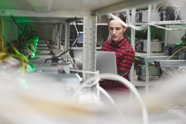 woman with laptop working on cryptocurrency mining farm 