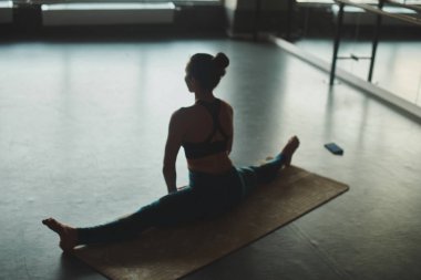 kadın ise dize üzerinde oturan ve pratik yoga mat spor salonunda esnekliğini göstererek