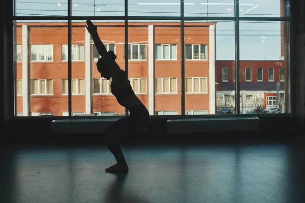 silhouette of woman practicing warrior yoga pose in gym, virabhadrasana pose