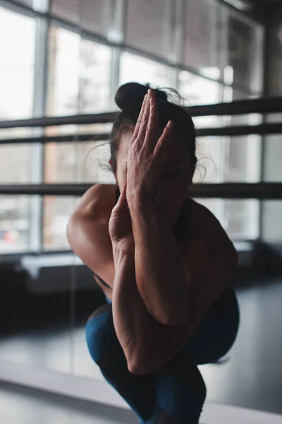 woman practicing yoga eagle pose in gym, garudasana  pose