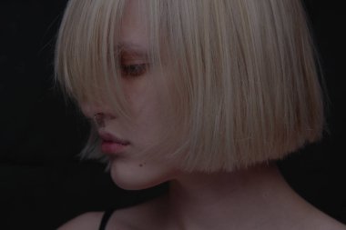 koyu arka plan üzerinde bob saç modeli ile sarışın kadın portresi 