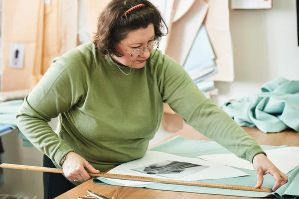 atelier giysilerle oluşturulması üzerinde çalışırken dikiş kalıpları kullanarak terzi konsantre