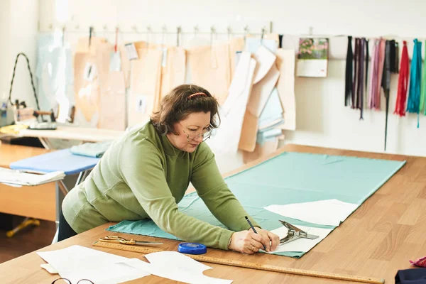 atelier giysilerle oluşturulması üzerinde çalışırken dikiş kalıpları kullanarak terzi konsantre