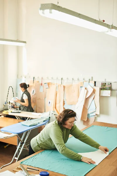 atelier giysilerle oluşturulması üzerinde çalışırken dikiş kalıpları kullanarak terzi konsantre