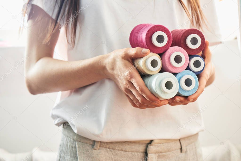 female seamstress holding collection of bright thread coils 