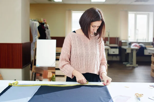 集中裁缝把纺织品放在桌子上 用胶带测量 在画室概念中创造衣服 — 图库照片