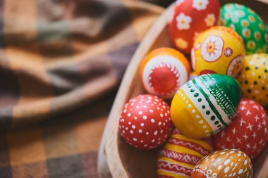 Damalı masa örtüsü arka plan üzerinde renkli boyalı Paskalya yığını ile ahşap kase yumurta 