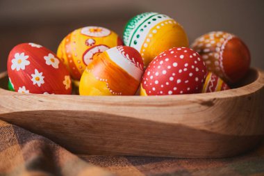 Damalı masa örtüsü arka plan üzerinde renkli boyalı Paskalya yığını ile ahşap kase yumurta 