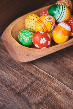 ahşap kase boyalı renkli Paskalya yığını ile kahverengi zemin üzerine yumurta 