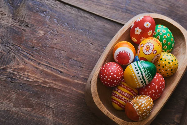 ahşap kase boyalı renkli Paskalya yığını ile kahverengi zemin üzerine yumurta 
