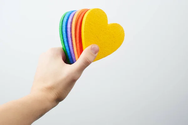 male hand holding hearts painted in rainbow colors isolated on white background , LGBT concept