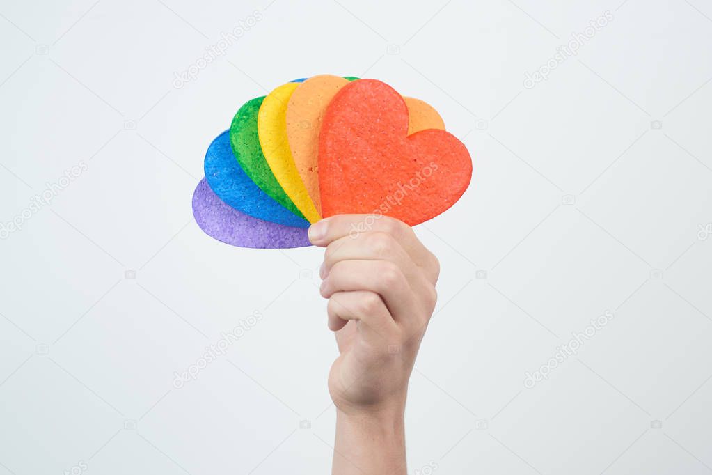 male hand holding hearts painted in rainbow colors isolated on white background , LGBT concept 