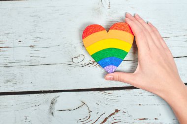 Gökkuşağı renkli ahşap arka plan, Lgbt kavramı üzerinde kalp tutan el boyalı 