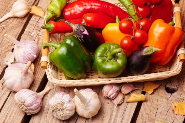 Kiraz domates, biber, sarımsak, bir hasır sepet Poğaca. Ahşap bir masa üzerinde taze sebze