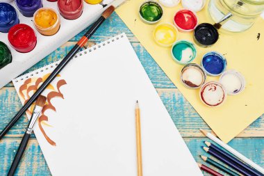 Boya kalemleri ve fırçalar ahşap arka plan hakkında kağıt ile yakın çekim