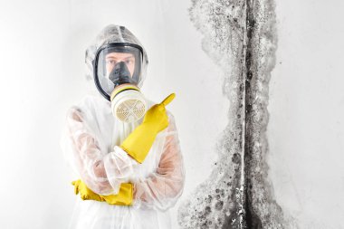 Tulum ve maske profesyonel bir dezenfeksiyon duvardaki siyah küf, bir parmak işaret eder. Apartman ve ev içinde mantar kaldırılması. Aspergillus