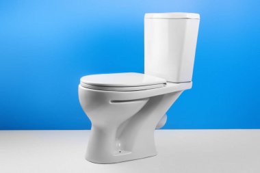 İzole beyaz mavi zemin üzerine beyaz tuvalet kase. Yan görünüm