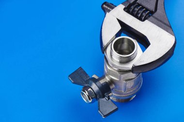 Sıhhi tesisat kavramı. Ayarlanabilir anahtarı vinç izole mavi bir arka plan üzerinde tutar..