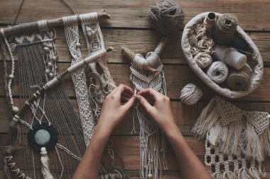 Female hands weaving macrame on a wooden table. Do it yourself. Top view. clipart