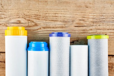 Su filtreleri. Ahşap arka plan üzerinde karbon kartuşları. Ev filtreleme sistemi.