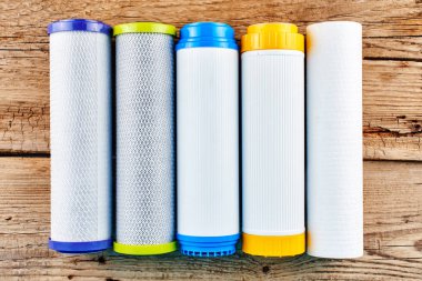 Su filtreleri. Ahşap arka plan üzerinde karbon kartuşları. Ev filtreleme sistemi.
