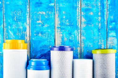 Su filtreleri. Mavi arka planda karbon kartuşları. Ev filtreleme sistemi.