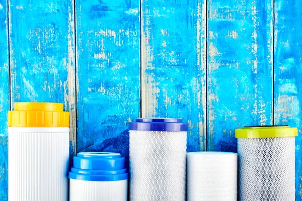 Su filtreleri. Mavi arka planda karbon kartuşları. Ev filtreleme sistemi.