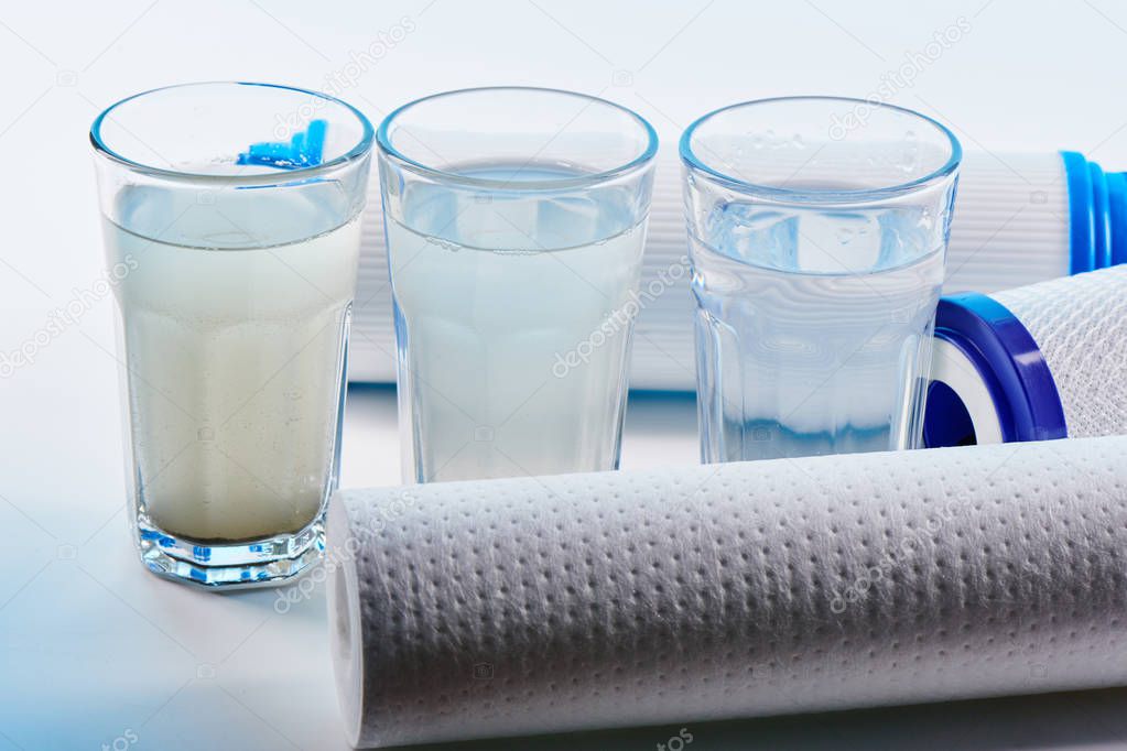 Water filters. Carbon cartridges and glasses on a white background. Household filtration system.
