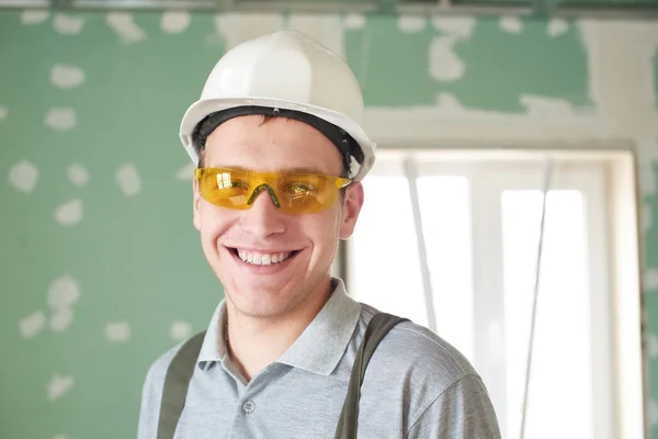 Reparação Quartos Sorrindo Jovem Construtor Capacete Óculos Fica Contra Fundo — Fotografia de Stock