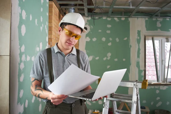 Room Repair Builder Helmet Glasses Stands Laptop Drawings His Hands — Stock Photo, Image