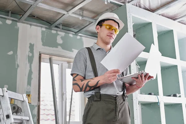 Room Repair Builder Helmet Glasses Stands Laptop Drawings His Hands — Stock Photo, Image