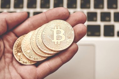 Fiziksel sembol cryptocurrency. Erkekler avucunun dizüstü bilgisayarınızın arka planında altın bitcoins. Blockchain kavramı