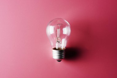 Pembe bir arka plan üzerinde ampul. Fikir ve oluşturma kökeni kavramı