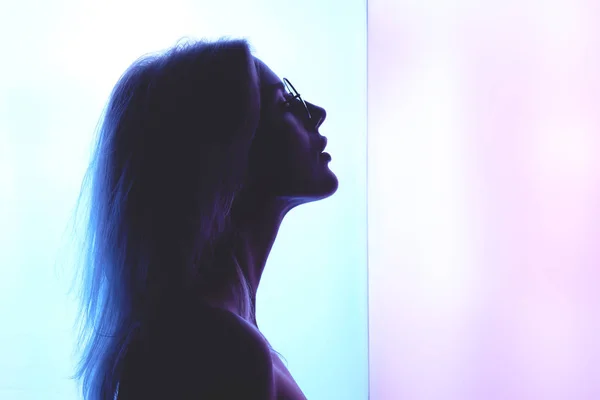 美しい若い金髪の女性とピンク 青色の背景にガラスのプロファイル — ストック写真