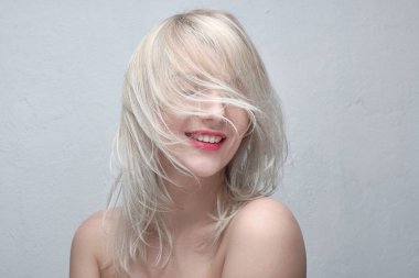 Genç güzel bir gülümseyen sarışın kadınla dolgun kırmızı dudaklar ve beyaz bir arka plan üzerinde çıplak omuz portre. Şık şık saç modeli