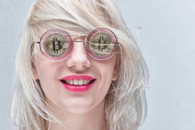 Portre sarışın, güzel bir genç gülümseyen kadın gözlük ile bitcoins beyaz bir arka plan üzerinde kırmızı dudaklı. Cryptocurrency kavramı