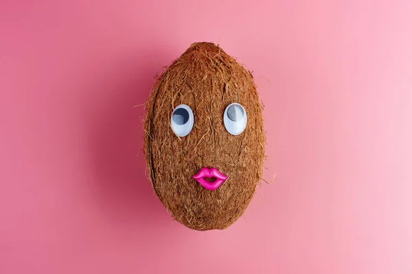 Exotic coconut with eyes and lips on a pink background