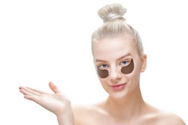 Mavi gözlü güzel bir genç sarışın kadın ve siyah göz yamalar ile dolgun dudaklar ürününüzü beyaz bir arka plan üzerinde izole senin avucunun içinde tutar. Maskeleri ve yüz bakımı