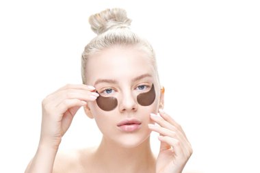 Güzel genç sarışın mavi gözlü koyarak veya göz yamalar izole beyaz arka plan yakın çekim üzerinde kaldırma. Maskeleri ve yüz bakımı