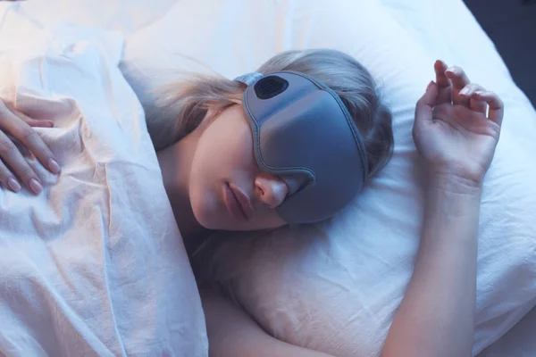 夜間照明付きの整形外科枕の睡眠マスクで女の子を寝て 白のベッドリネン — ストック写真