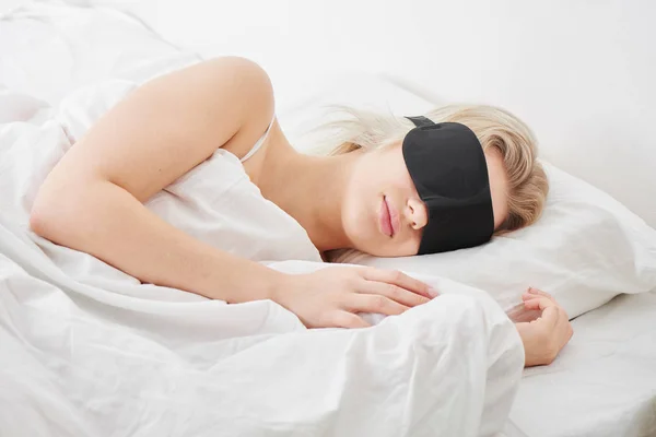 眠っている女の子の明るい日光の下 白い寝具の整形外科枕で寝ている黒いマスクの — ストック写真