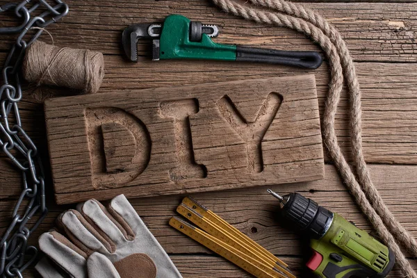 DIY letters on a wooden board on the background of working tools. Do It Yourself concept.